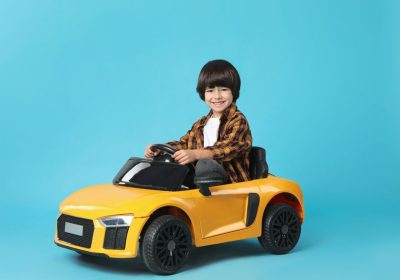 Little,Child,Driving,Yellow,Toy,Car,On,Light,Blue,Background